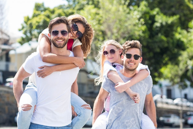 Hip men giving piggy back to their girlfriends on the street