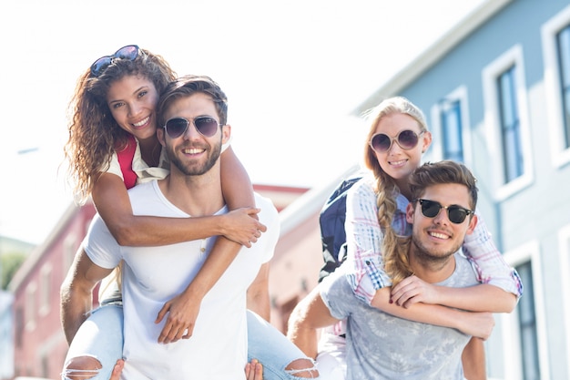 Hip men giving piggy back to their girlfriends on the street