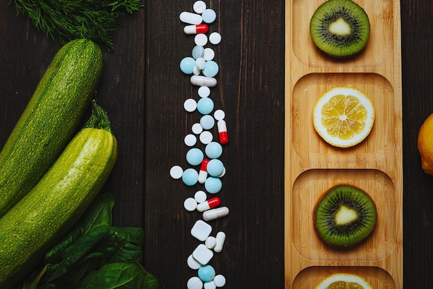 Foto hip di pillole con fette di limone e kiwi concetto di pasto sano frutta contro la medicina