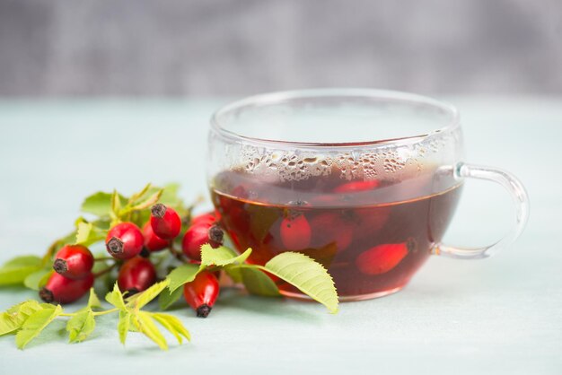 Hip rose tea with fresh fruits and leaves, hot drink in autumn and winter