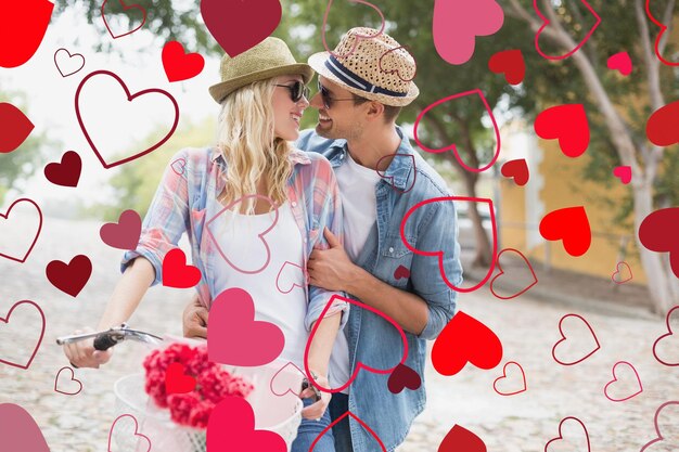 Hip young couple going for a bike ride against valentines heart design