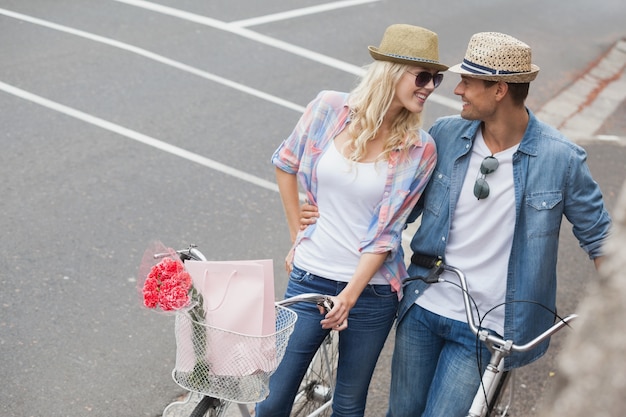 ヒップの若いカップルが自転車に乗る