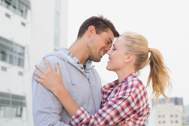 Hip young couple hugging about to kiss