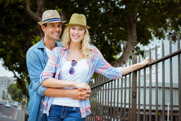 Hip young couple smiling at camera by railings