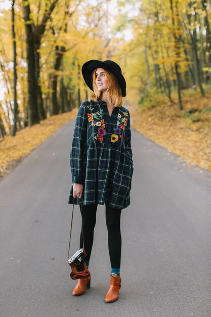 Photo hippie girl with old camera in a hat walks autumn park.