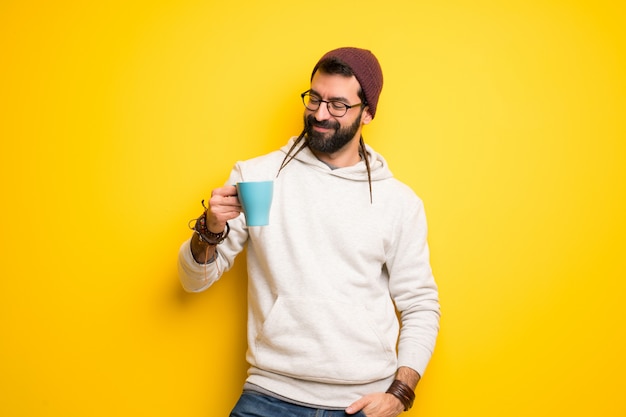 熱い一杯のコーヒーを保持しているドレッドヘアを持つヒッピー男