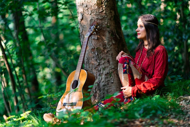 Hippie meisje met de gitaar in het bos