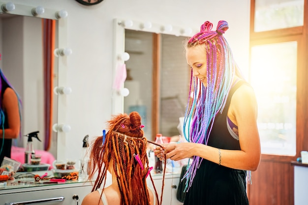 Hippie style hair woman hairdresser with colored afro braids weaves to girl ginger dreadlocks weavin...