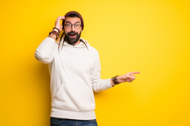 Hippiemens die met dreadlocks vinger aan de kant richten en een product voorstelt