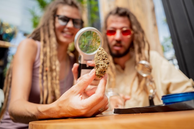 Hippiestijlpaar onderzoekt onder een vergrootglas de gewrichten en toppen van medicinale marihuana