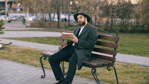 Hipser creative artist man in hat and coat drawing with pen and sketchbook