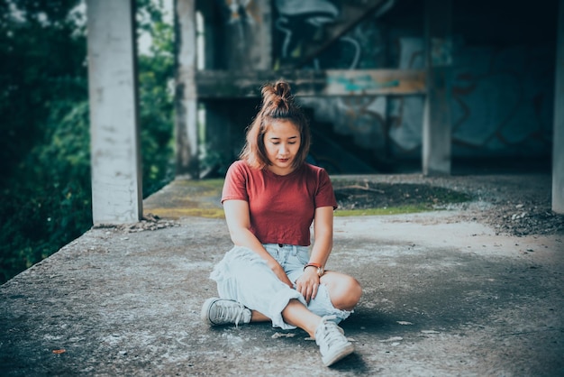 La donna grassa asiatica dei pantaloni a vita bassa si siede sulla posa del pavimento per scattare una foto della gente di stile dell'annata della tailandia