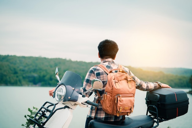 Hipster-backpacker rijdt op een motorscooter op de weg Reist per scooter langzaam leven op vakantie rusttijd