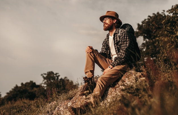 Hipster backpacker zittend op steen en ontspannen