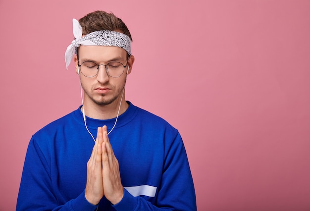 Hipster in bandana and glasses folded hands together praying