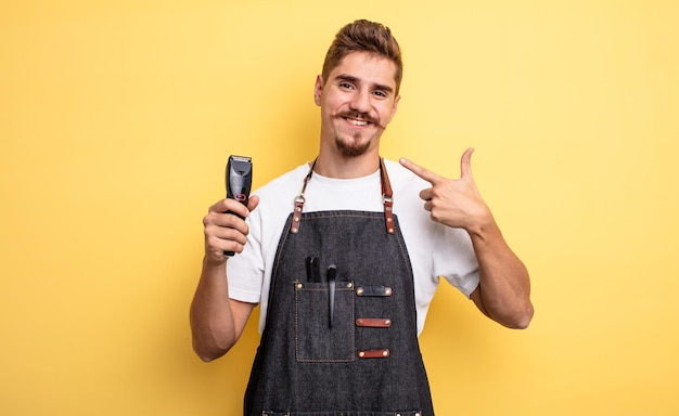 Hipster barber man smiling confidently pointing to own broad smile