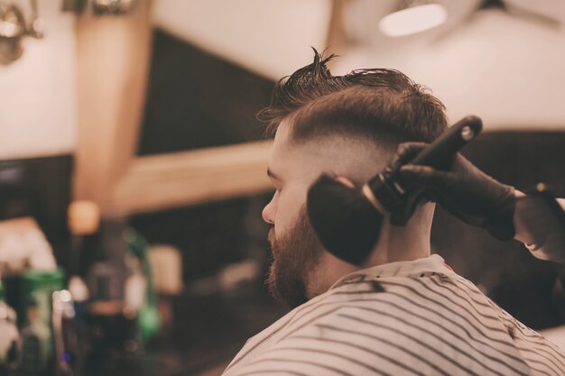 Hipster bearded man getting haircut in salon