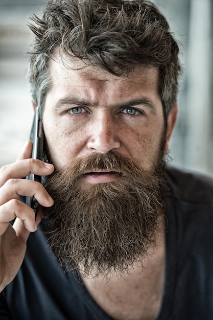 Hipster bebaarde communiceren smartphone-oproep. mobiele communicatie. communicatieconcept. man met baard en snor mobiele telefoon gesprek intreepupil achtergrond. bebaarde man houdt mobiele telefoon vast.