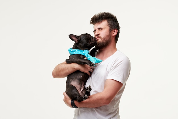 Hipster bebaarde man houden en knuffelen een mooie Franse Bulldog hond in zijn armen met liefde en spelen met hem