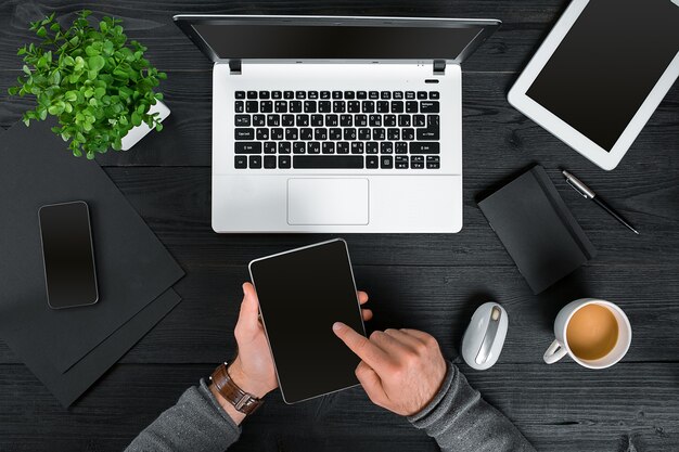 Hipster black wooden desktop top view male hands typing on a laptop