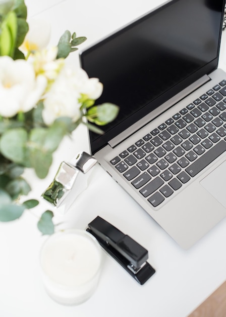 Hipster bloggers work place laptop and flowers on white tabletop