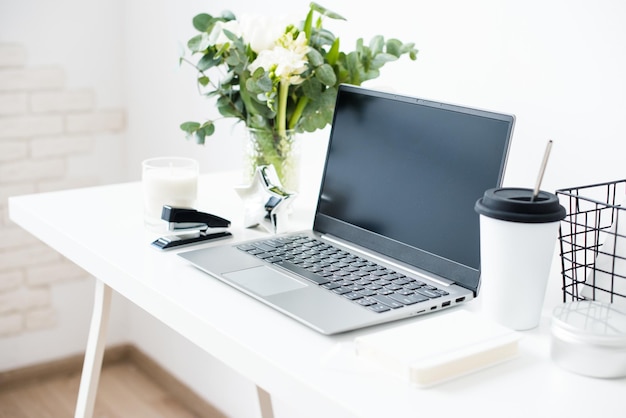 Hipster bloggers work place laptop and flowers on white tabletop