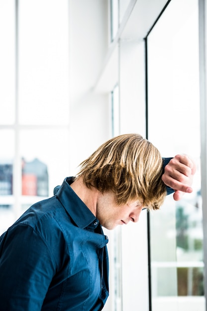 Hipster businessman looking out the window in his office