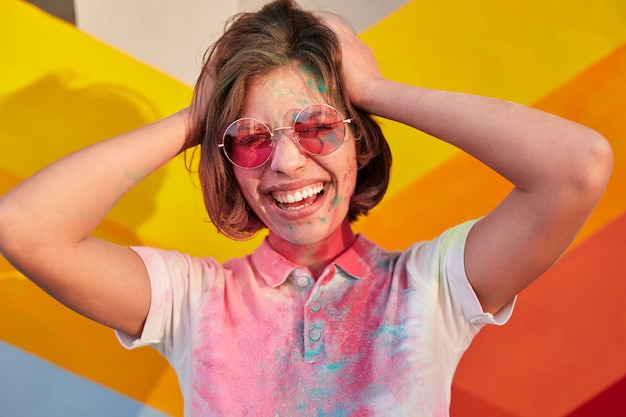 Photo hipster covered with colorful paint laughing