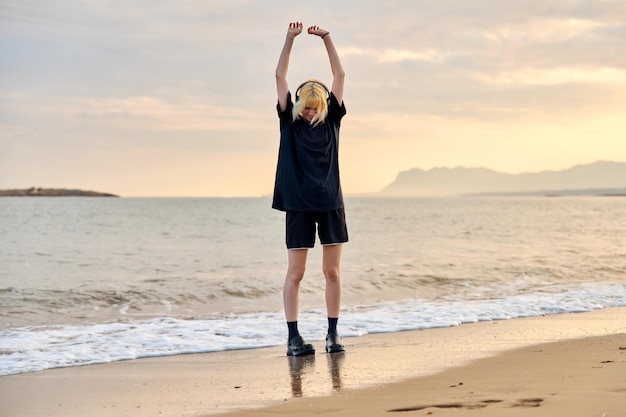 Hipster female teenager having fun on the beach at sunrise