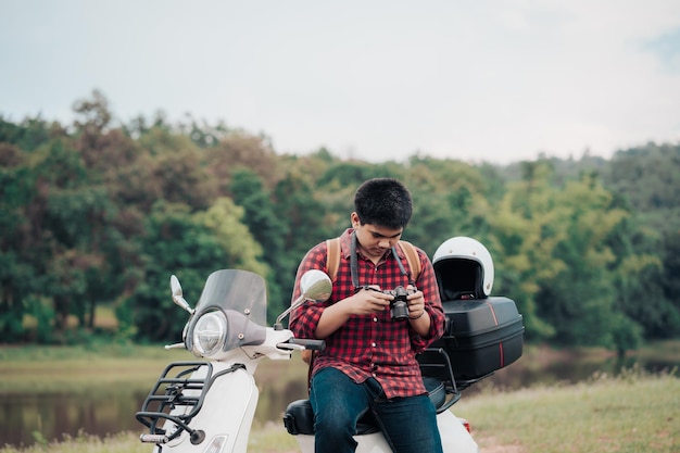 Hipster-fotograaf die op een scooter rijdt op de weg Reisde per scooter langzaam leven op vakantie rusttijd