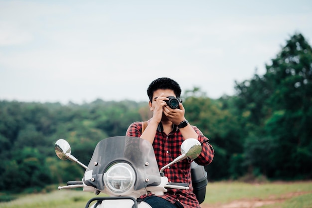 Foto hipster-fotograaf die op een scooter rijdt op de weg reisde per scooter langzaam leven op vakantie rusttijd