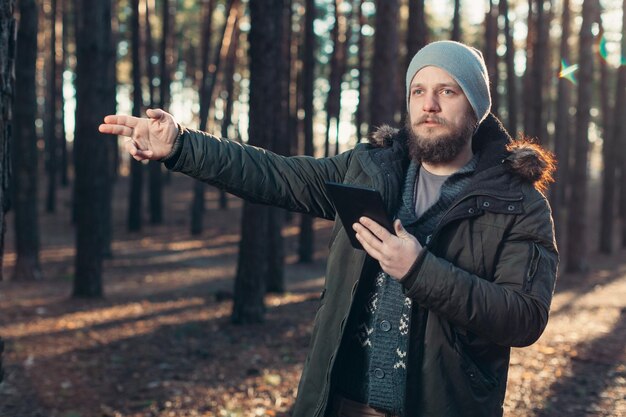 Hipster gesturing while holding digital tablet in forest