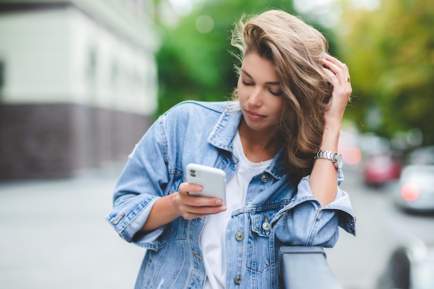 Hipster girl in clean white tshirt and jeans posing against the background of buildings