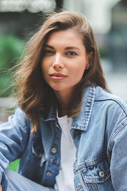 Hipster girl in clean white tshirt and jeans posing against the background of buildings