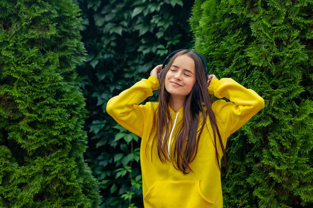 Hipster girl enjoys favorite music song in wireless headphones on a Sunny day