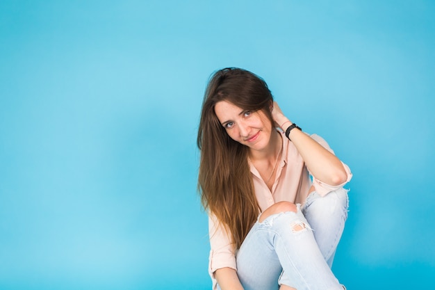 Hipster girl sitting on floor against blue background