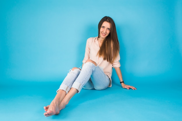 Hipster girl sitting on floor against blue