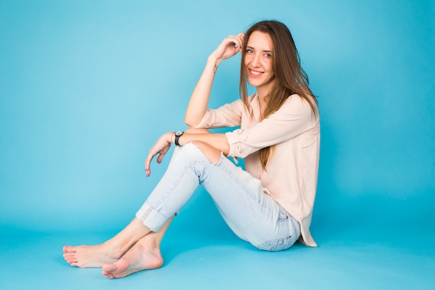 Hipster girl sitting on floor against blue