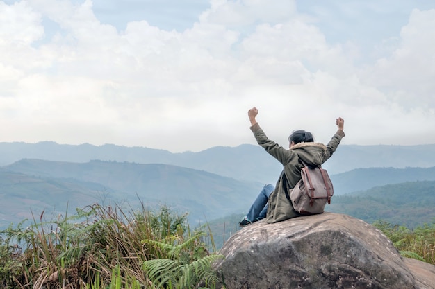 Hipster girl sitting in rocky of mountain  