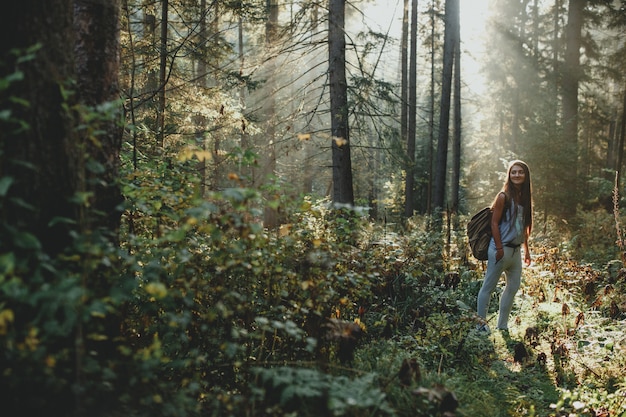 Hipster girl tourist with backpack is traveling in the woods