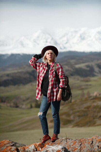 Foto hipster ragazza viaggiatore con cappello e zaino sullo sfondo delle montagne