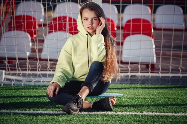 Hipster girl with skateboard outdoors Modern girl with a skateboard walking on a stadium Rest from study Outdoors Lifestyle