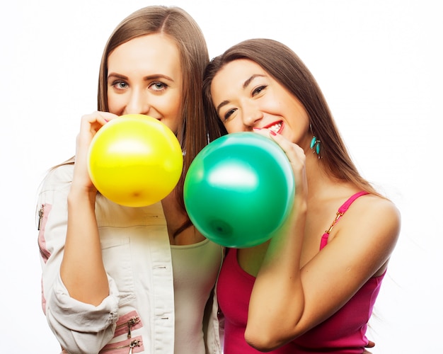 Hipster girls smiling and holding colored balloons