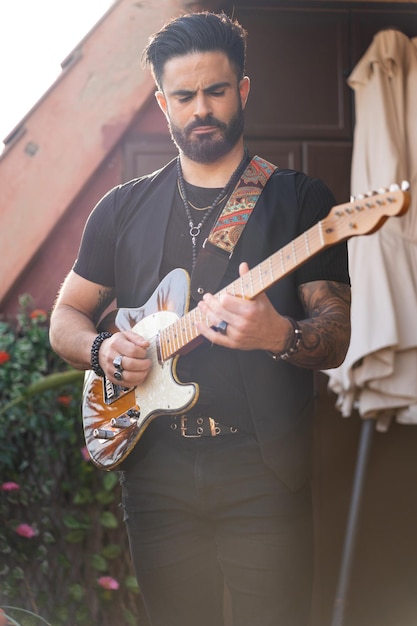 Foto gitarrista hipster che suona una chitarra elettrica all'aperto