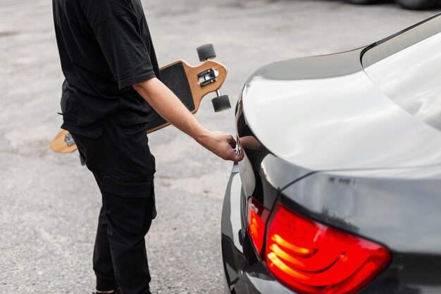 Hipster guy with a longboard opens the trunk of the car Travel and active recreation