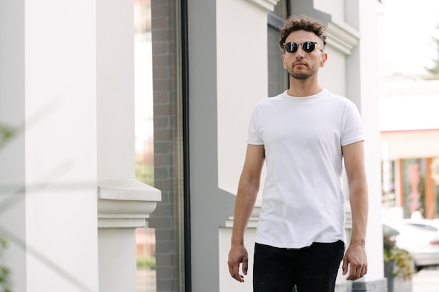 Hipster handsome male model wearing white blank tshirt with space for your logo or design in casual urban style