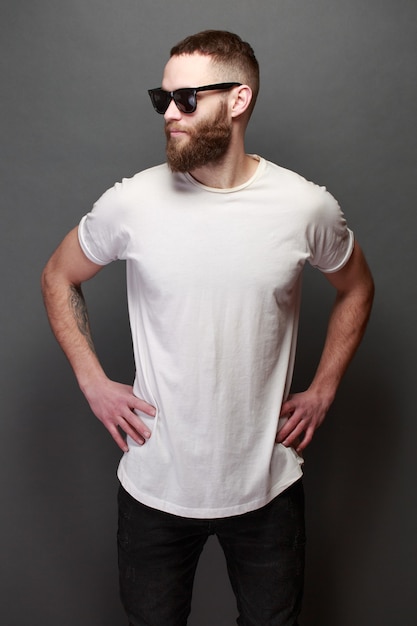 Hipster handsome male model with beard wearing white blank t-shirt with space for your logo or