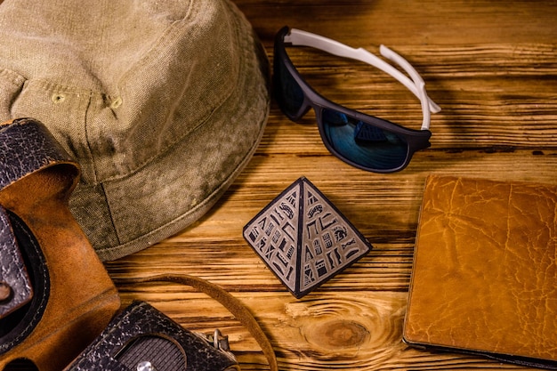 Hipster hat vintage camera sunglasses souvenir pyramid and passport on a wooden background Travel to Egypt