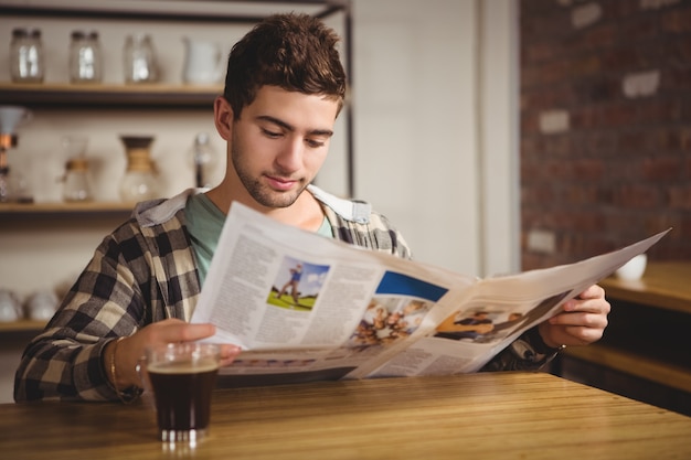 Hipster having coffee and reading newspaper at coffee shop