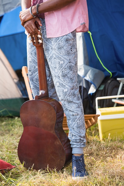 Hipster holding guitar at campsite